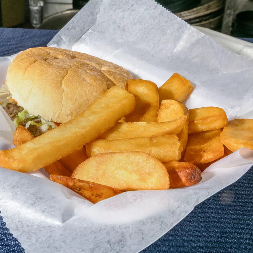 A burger with lettuce and a side of golden-brown french fries in a paper-lined basket.